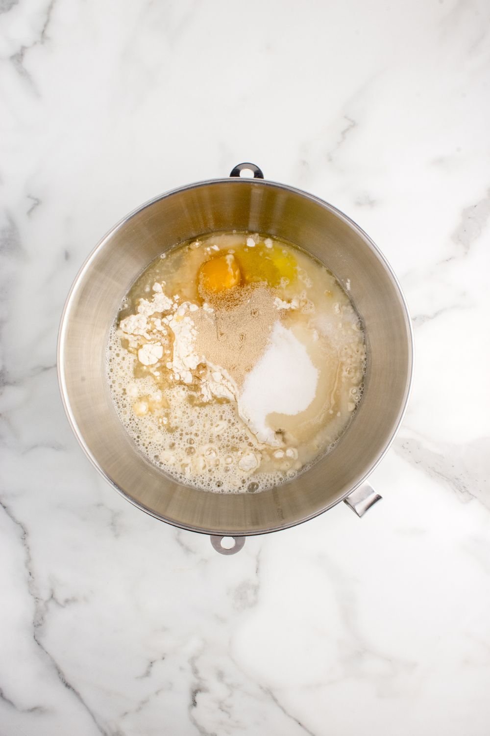 ingredients to make pull apart rolls in a mixing bowl on counter 
