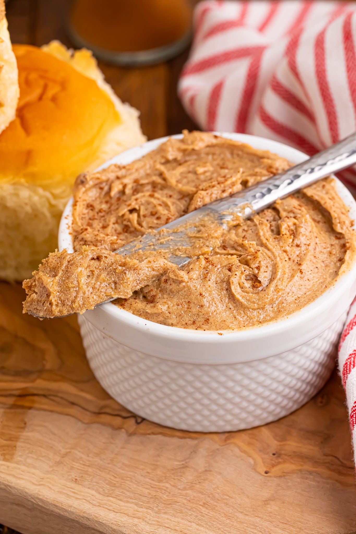 Up close shot of Brown Sugar Cinnamon Butter in a small container on table with a knife on top of bowl