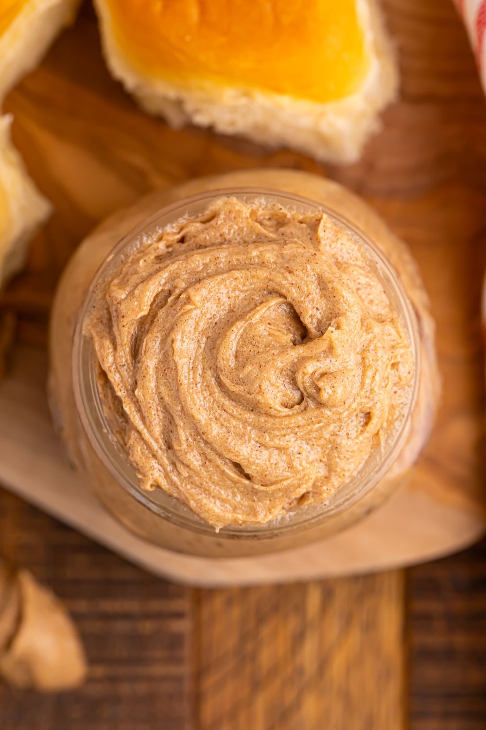 overhead look of cinnamon butter in a glass jar sitting on wooden cutting board on table 