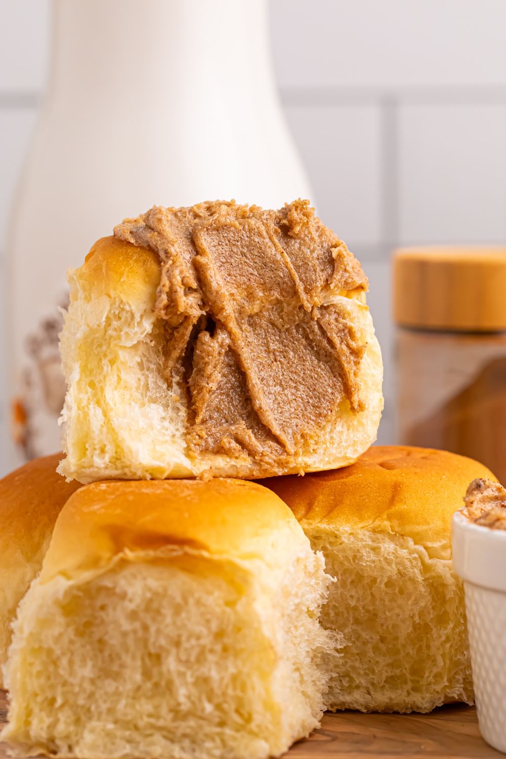 Brown Sugar Cinnamon Butter spread on a roll that is cut in half and stacked on top of more rolls 