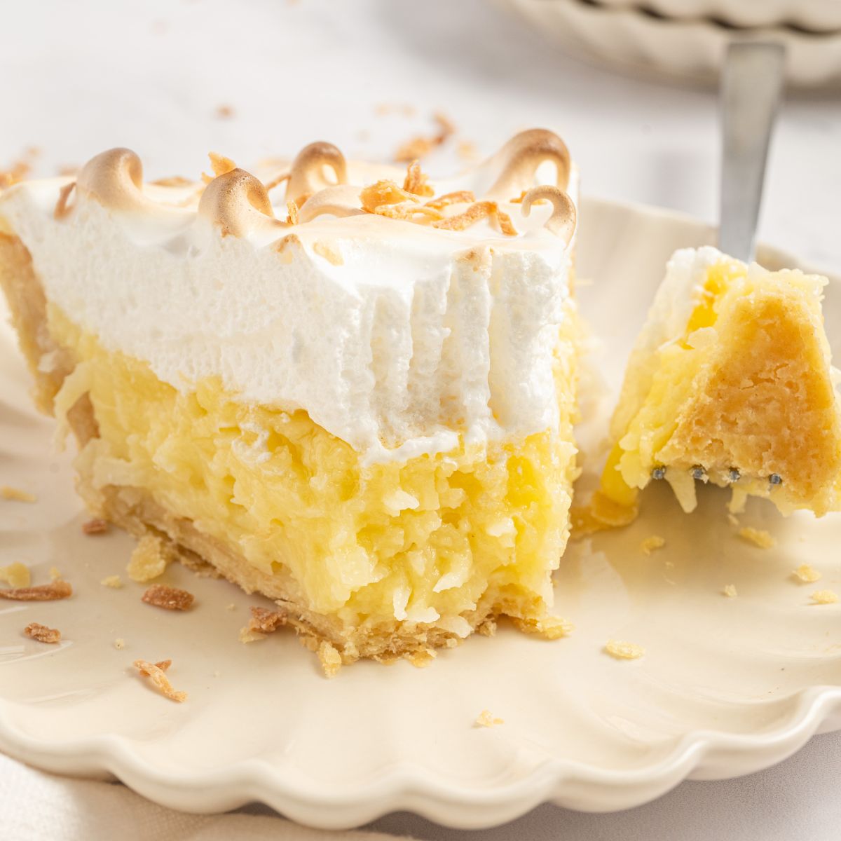 Coconut Meringue Pie on a plate with a fork with a bite on it  