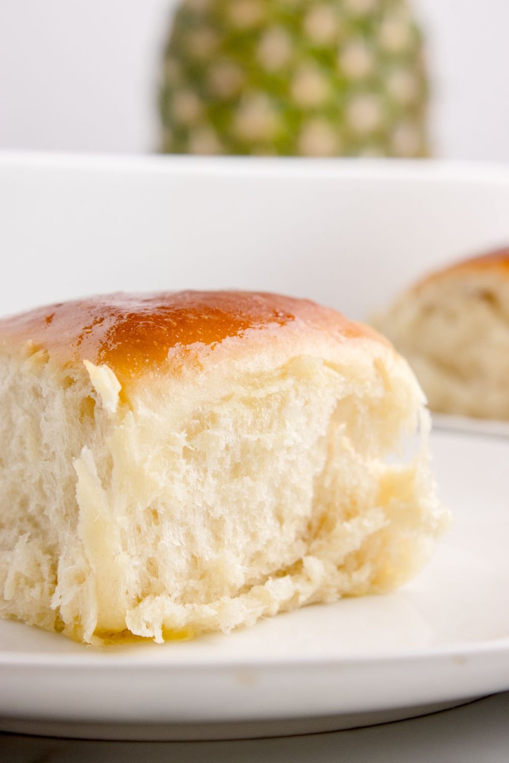 fluffy Hawaiian roll sitting on table with a pineapple sitting in the background