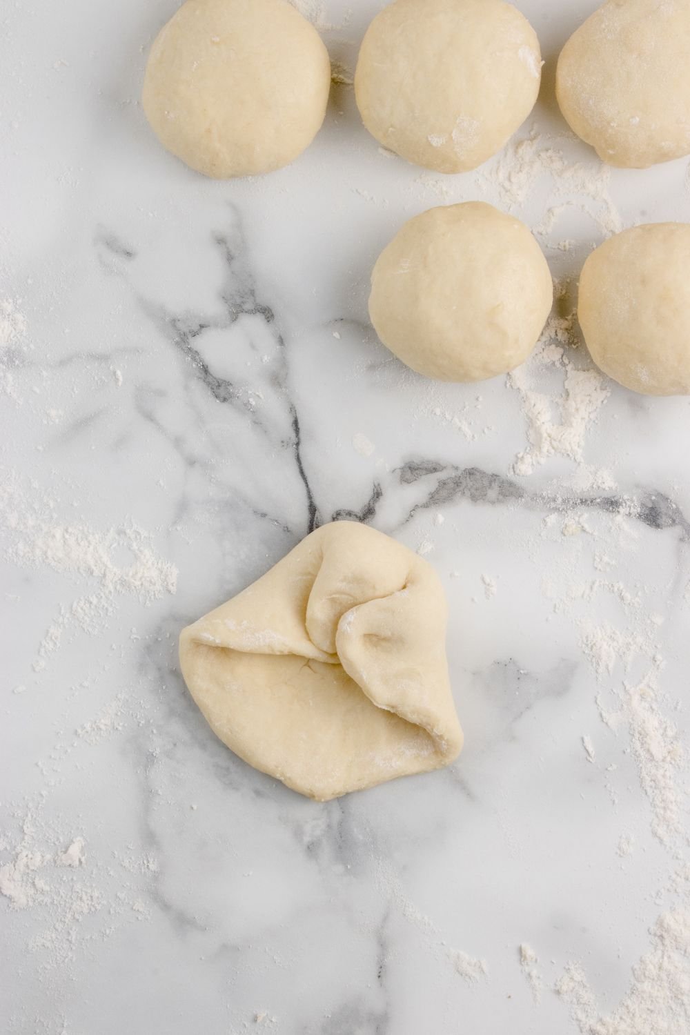 folding up bread dough in balls for making Hawaiian rolls