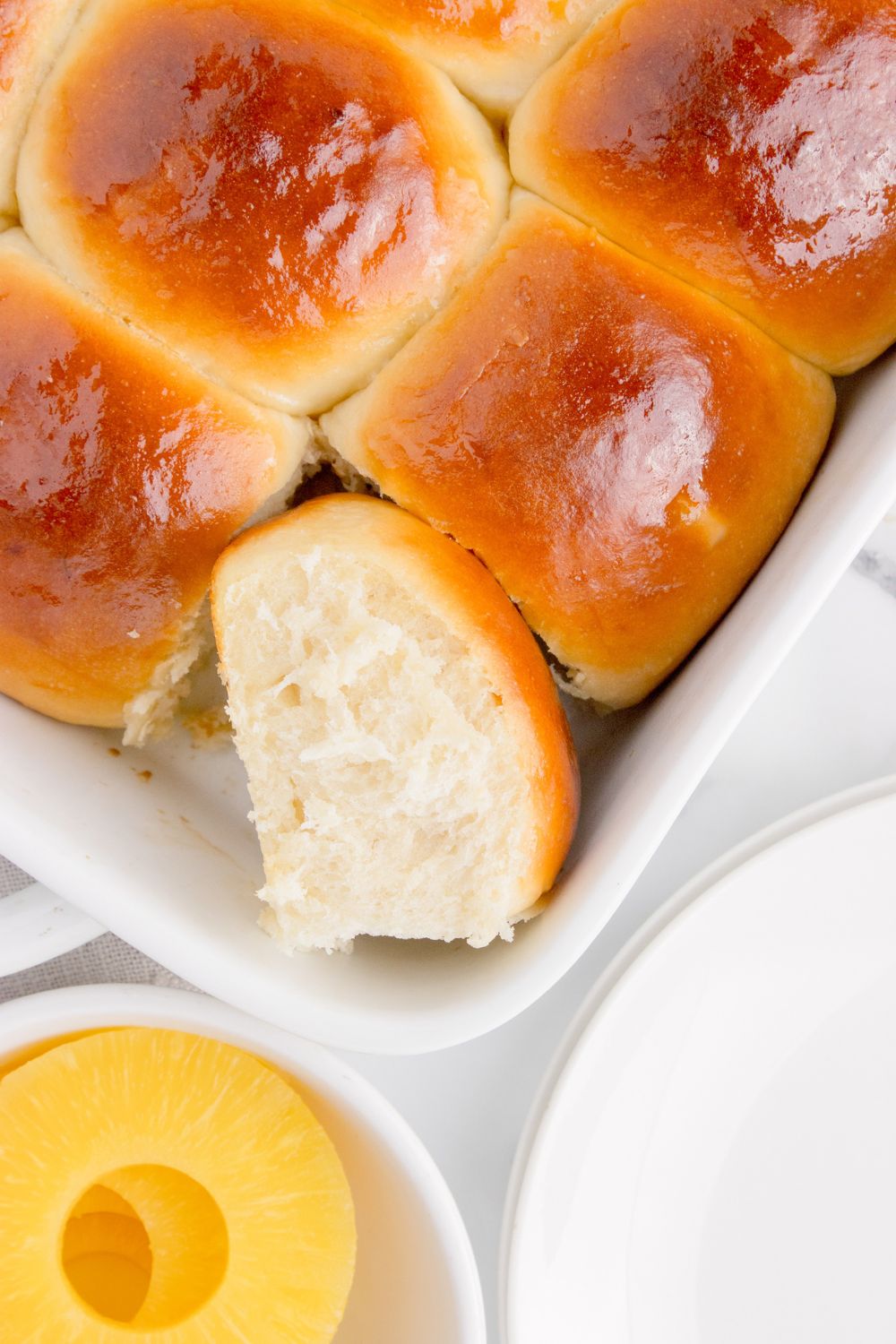 Hawaiian Dinner Rolls in a pan with one tilted on the side to show fluffy texture 