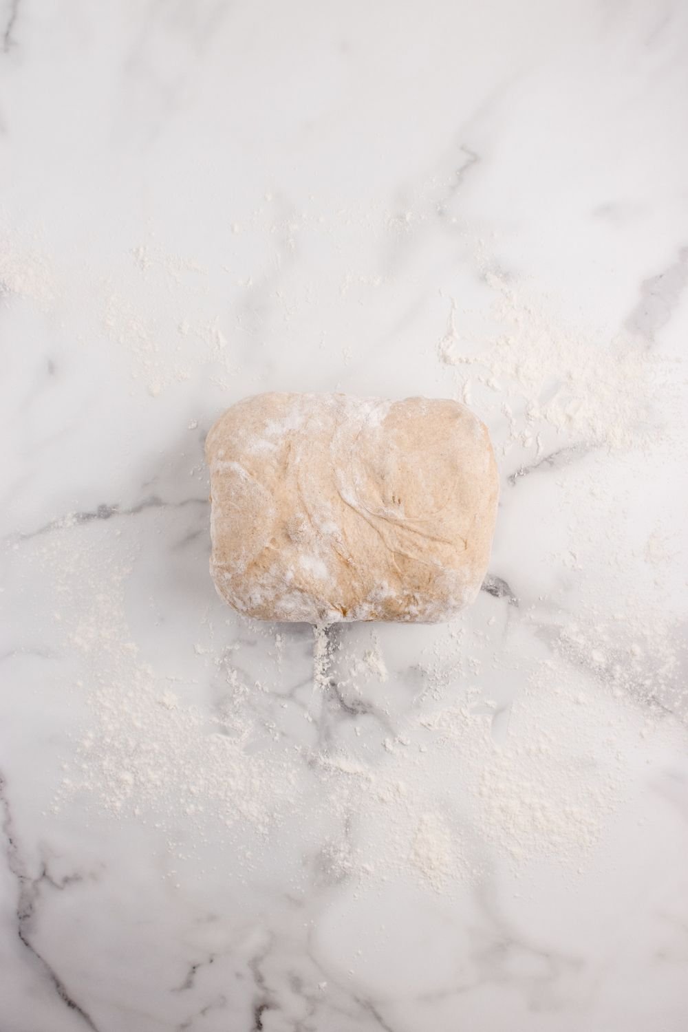 rolled bread dough on a marble countertop 