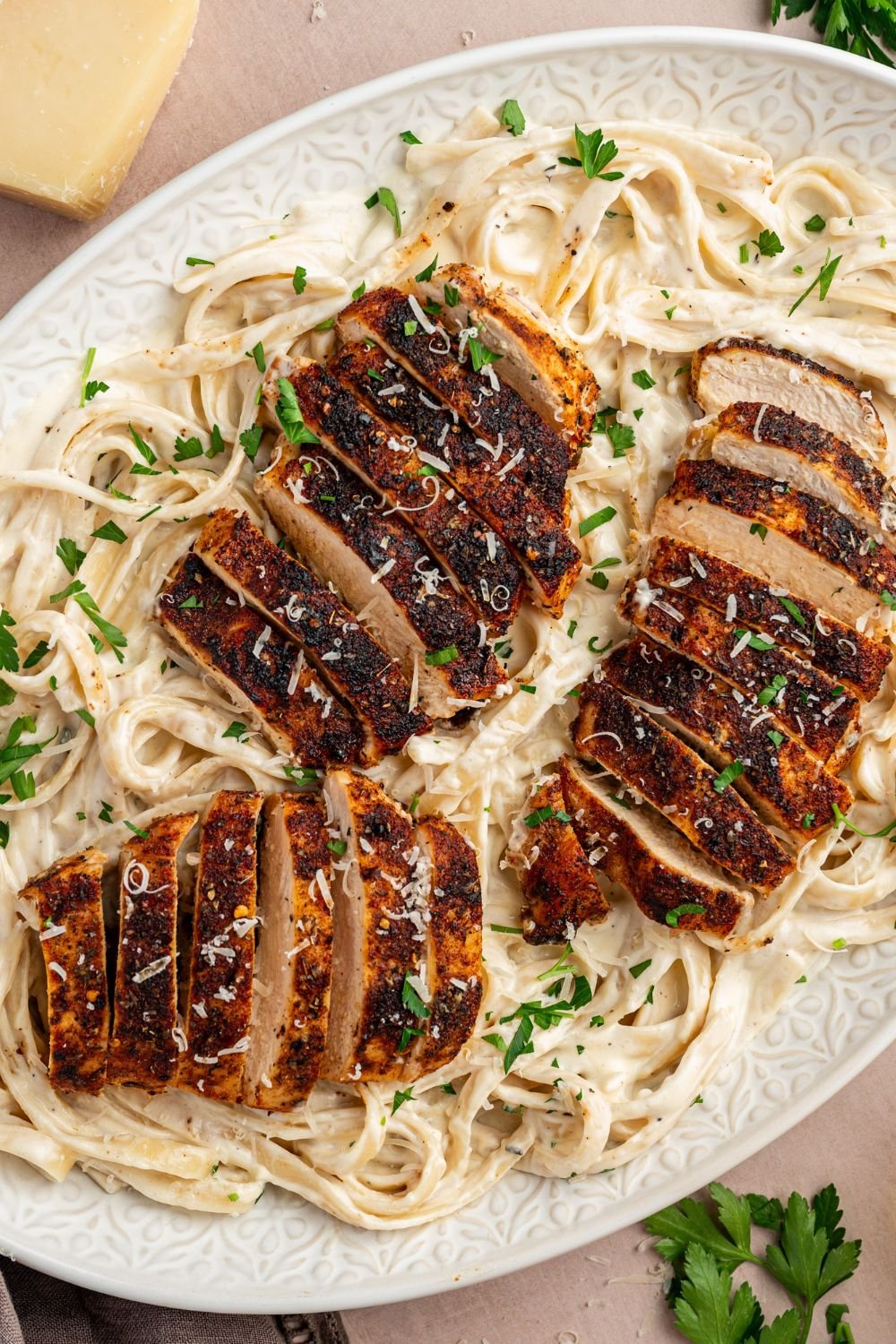 Blackened Chicken Alfredo in a large casserole dish with garnish on top of it 