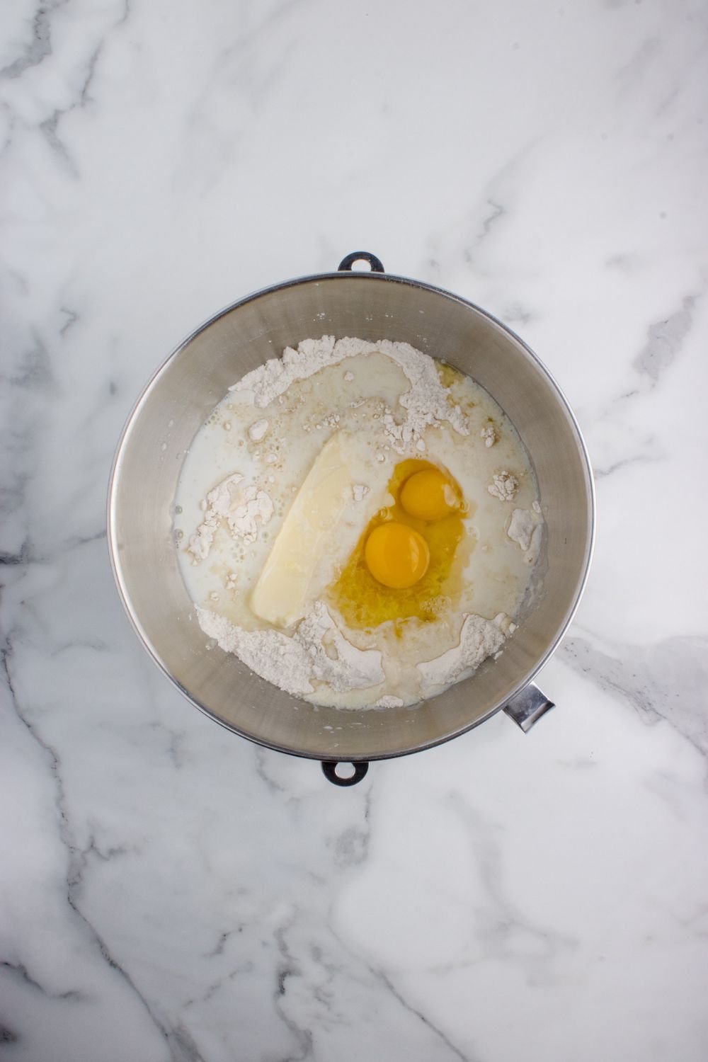 butter and eggs in a flour mixture in a mixing bowl on table for Hawaiian rolls