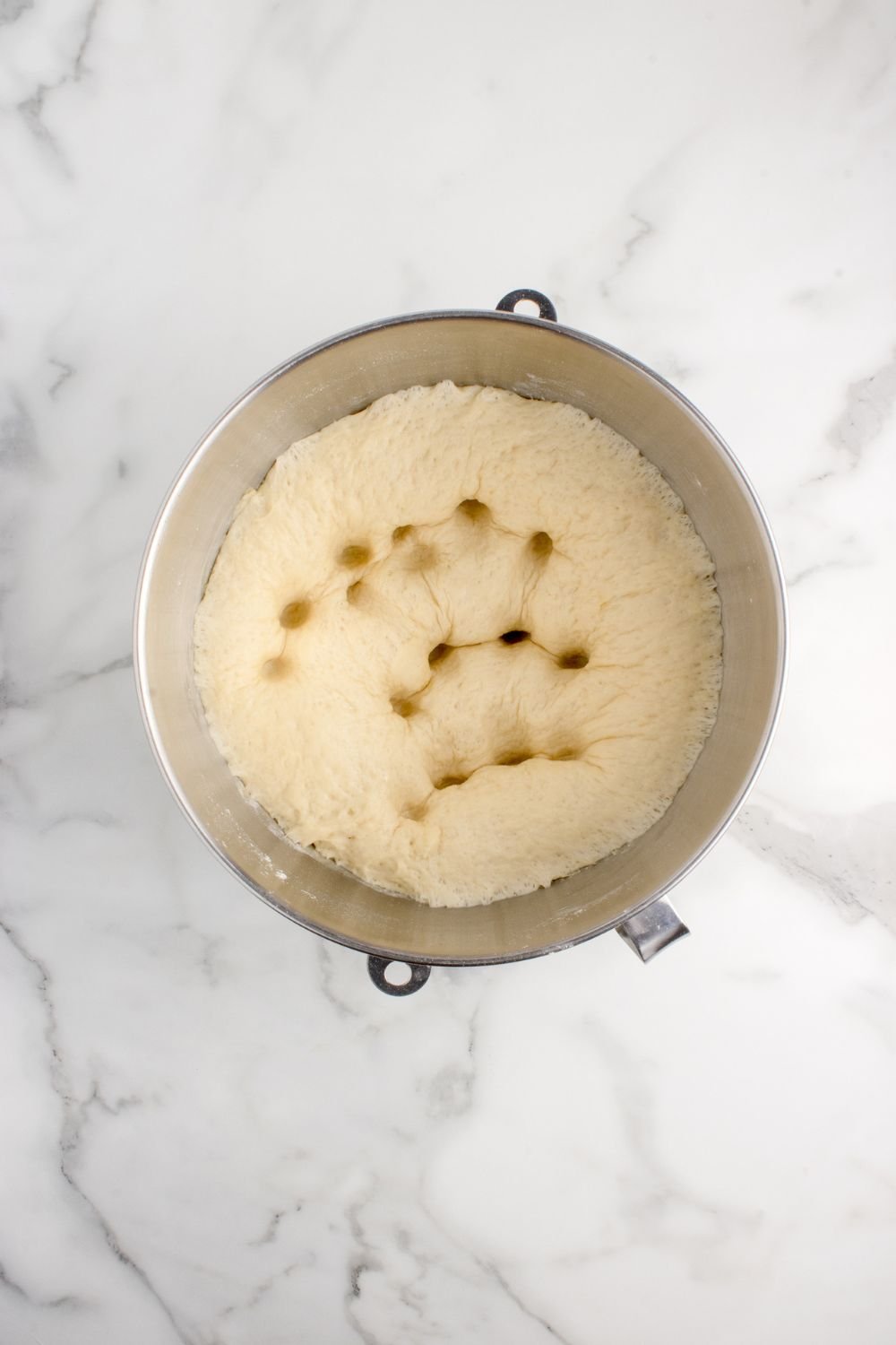 risen dough for pull apart rolls in mixing bowl punched down with fingers 