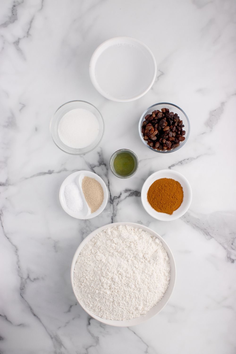ingredients for this No-knead Cinnamon Raisin Bread in containers on marble countertop 