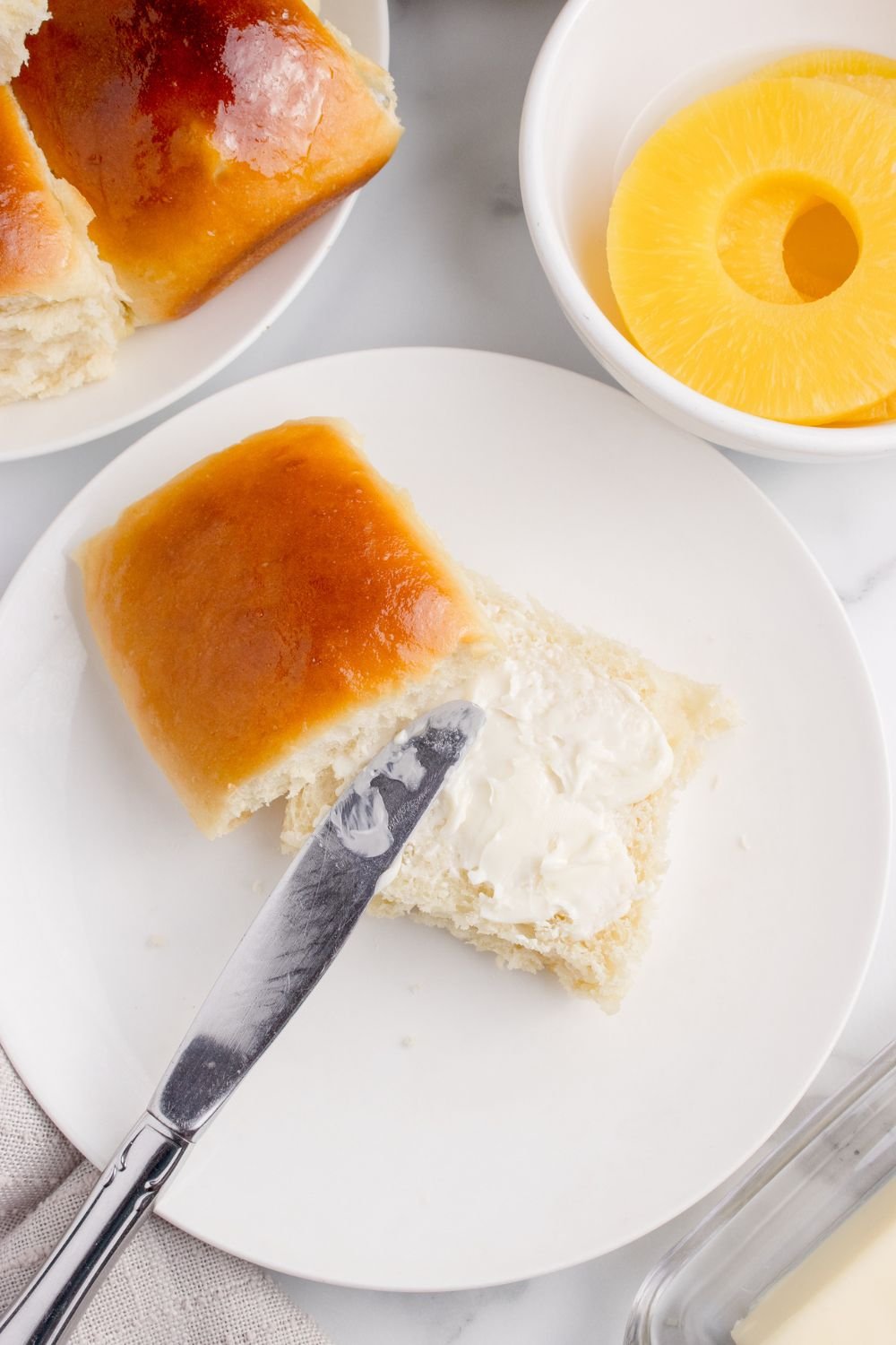 dinner roll with butter spread on top of it on plate 