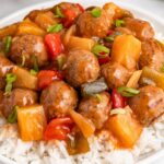 Crock Pot Sweet And Sour Meatballs piled on a bed of rice on plate