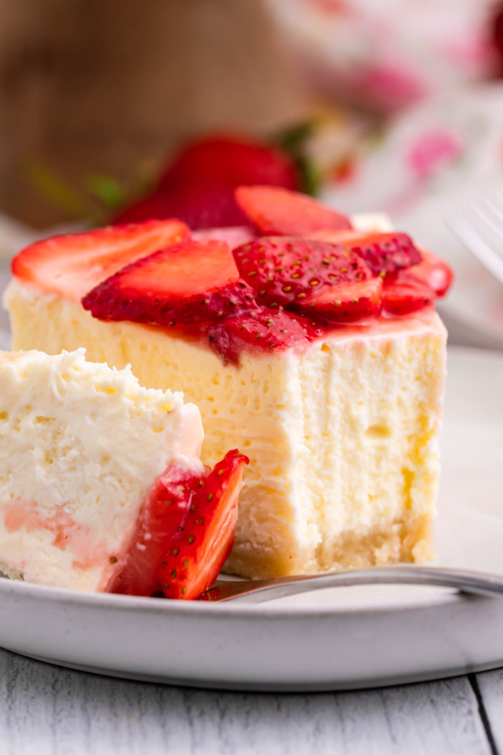 Keto cheesecake on a white plate with strawberries on top