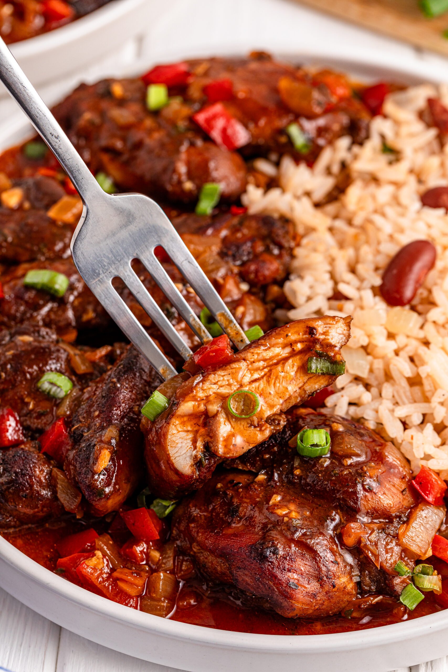 Jamaican Brown Stew Chicken with a bite being lifted up on a fork