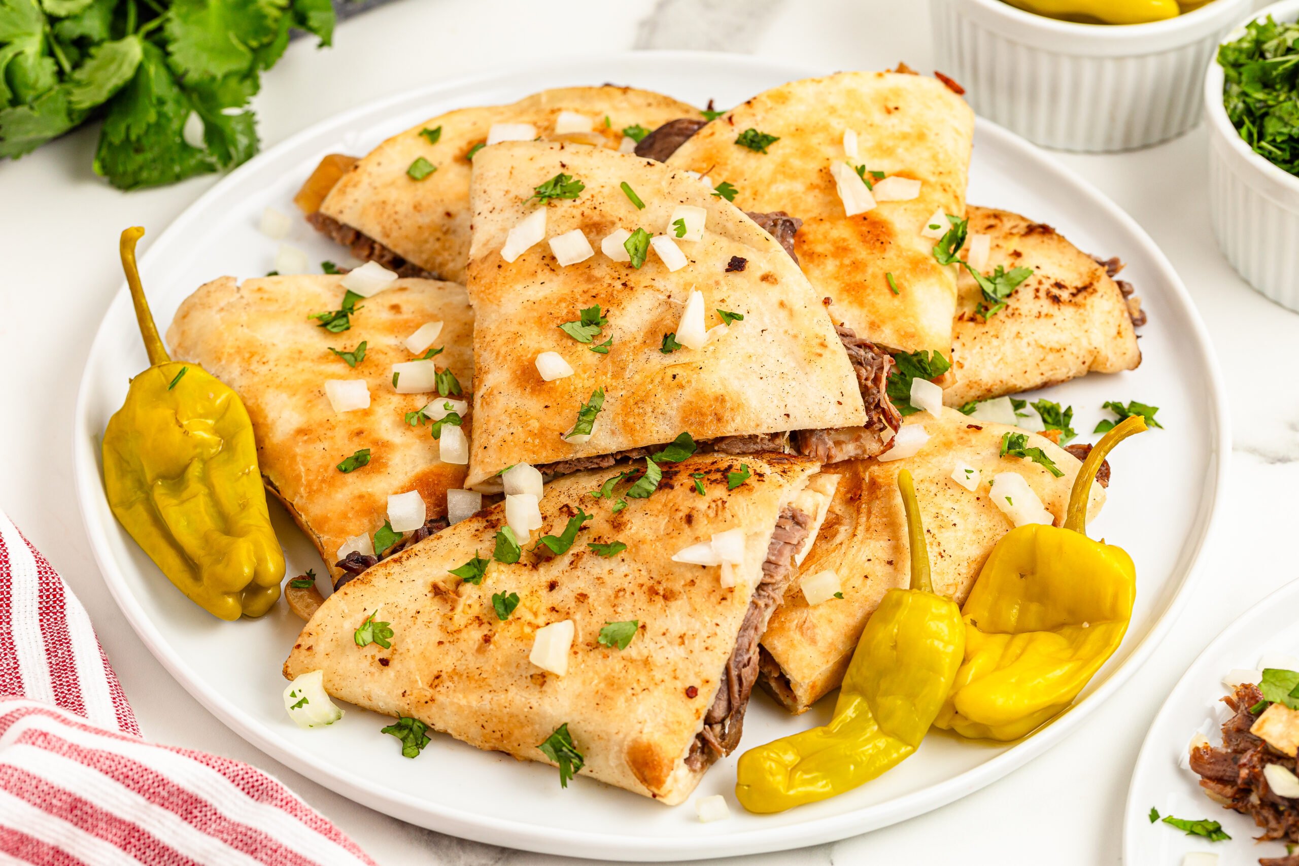 Mississippi Pot Roast Quesadillas piled on a plate  topped with onions 