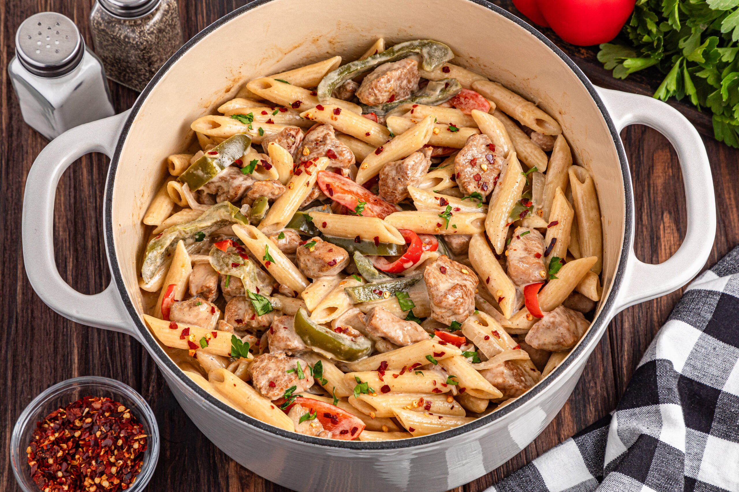 up close view of the Rasta Pasta in a large pot on a dark wooden table with salt and pepper shakers in the photo
