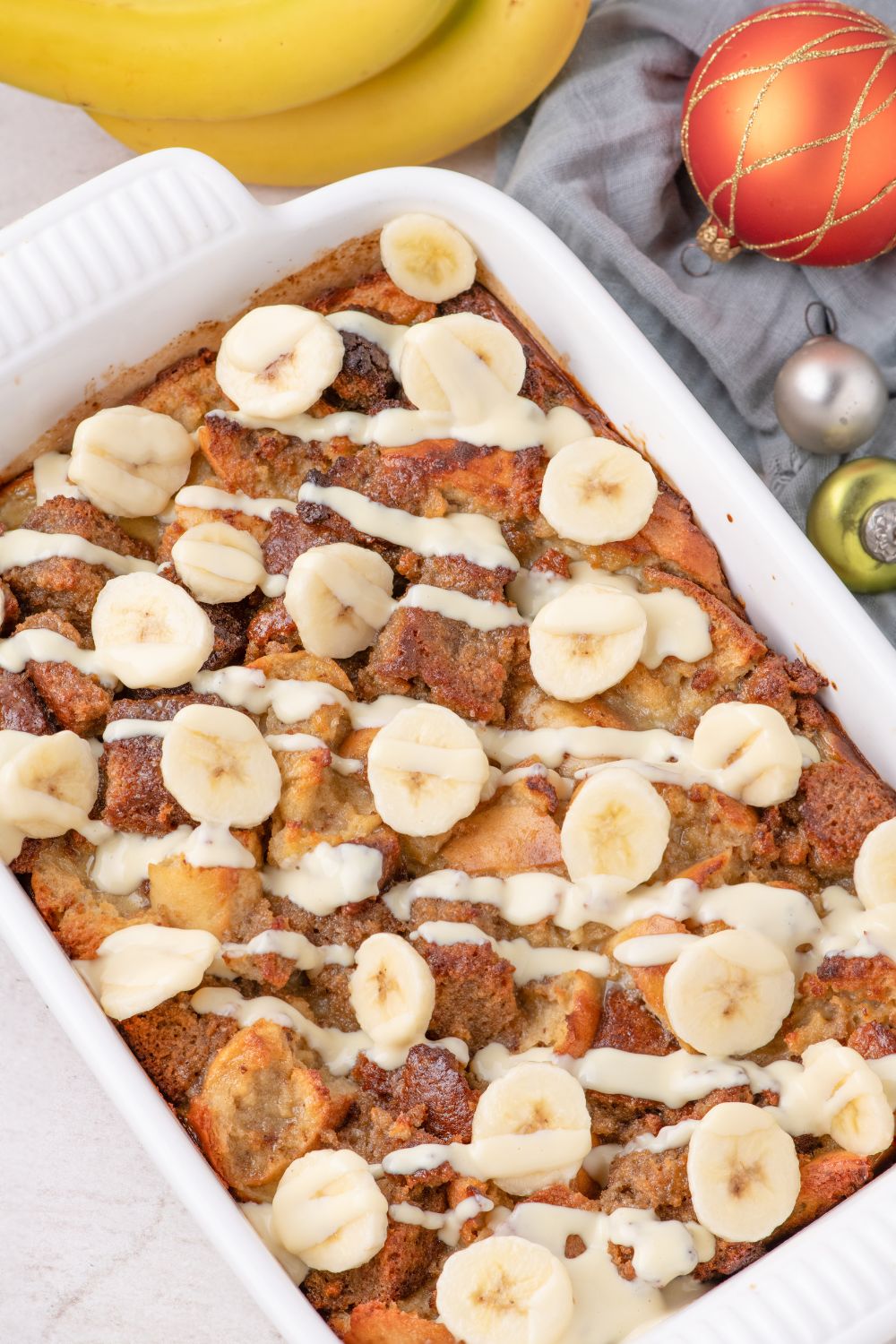 overhead Banana Bread Pudding in dish on table with christmas ornaments around it 