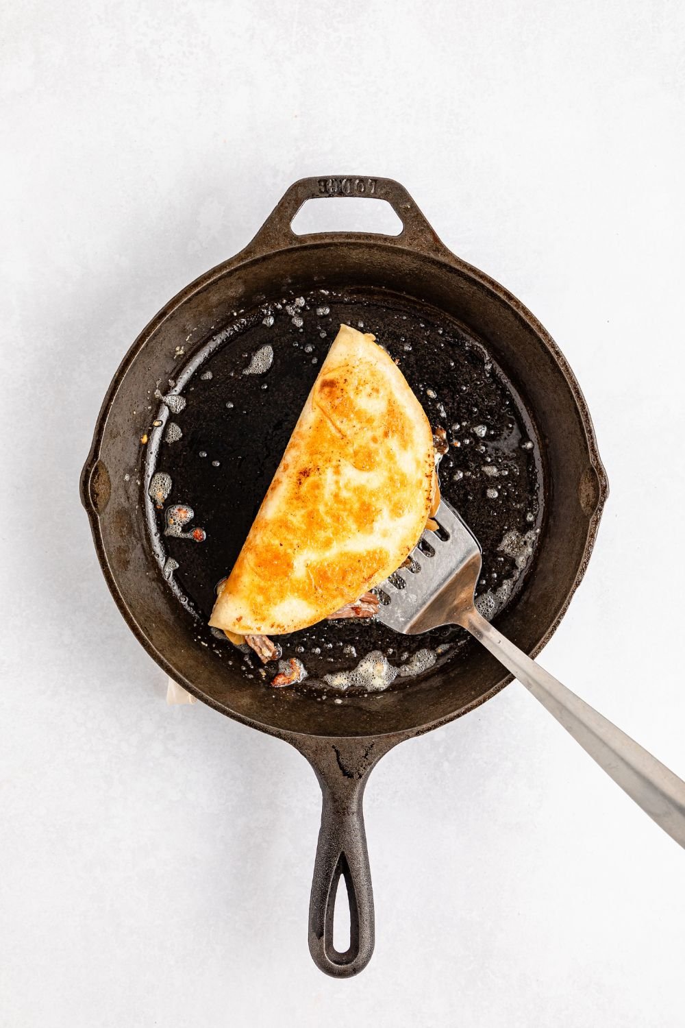 Mississippi Pot Roast Quesadillas in a skillet with a spatula under it 
