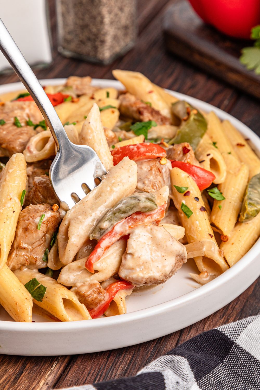 fork with some chicken from the rasta pasta poked in it off the plate