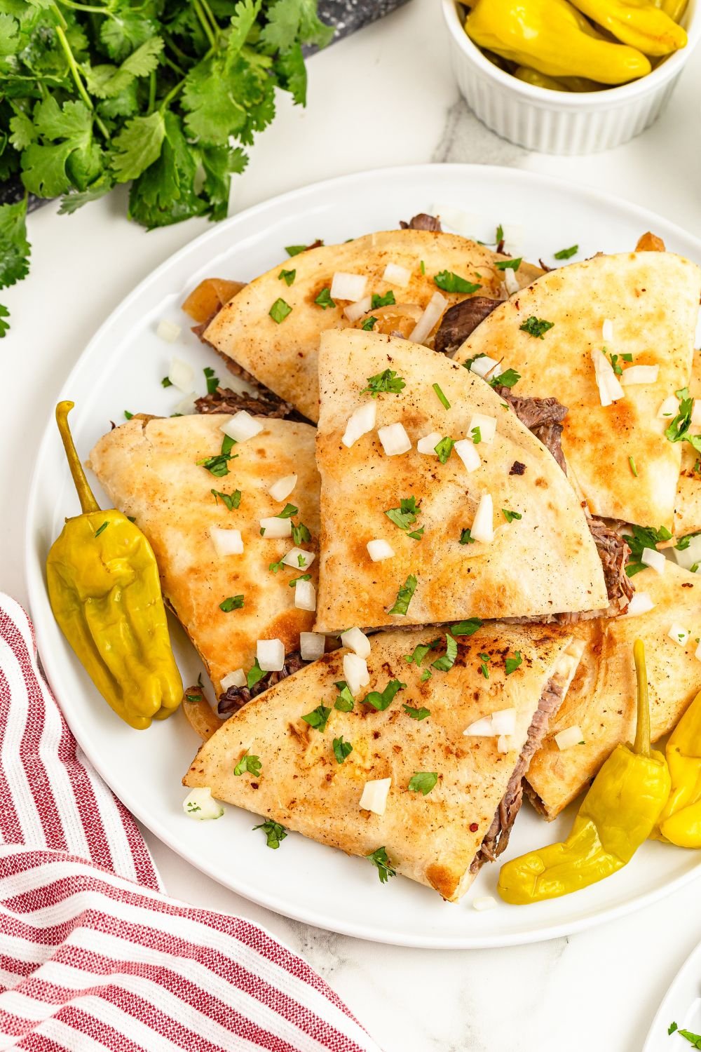 Mississippi Pot Roast Quesadillas on platter with cilantro, peppers and more all around the table 