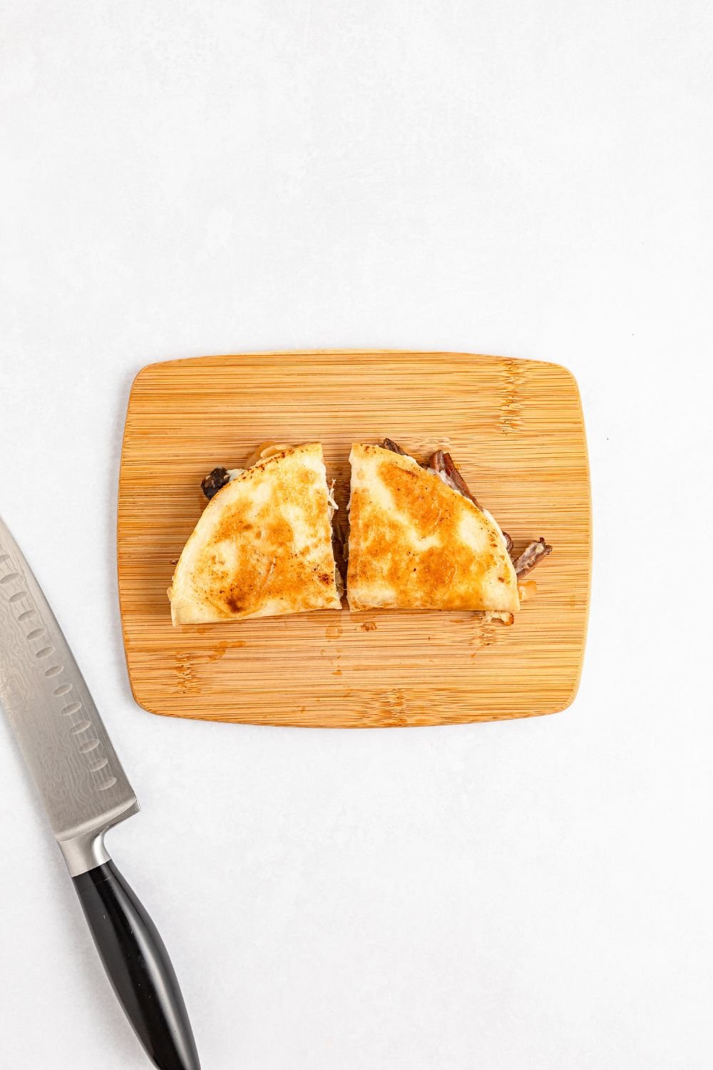 Mississippi Pot Roast Quesadilla on a cutting board with a slice in half 