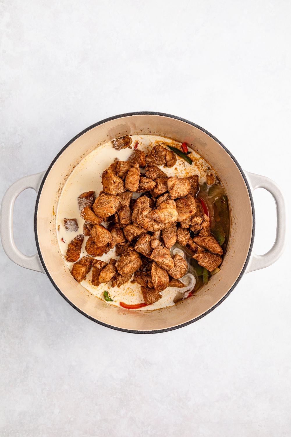 seared Jamaican jerk chicken in a stockpot with heavy cream for rasta pasta 