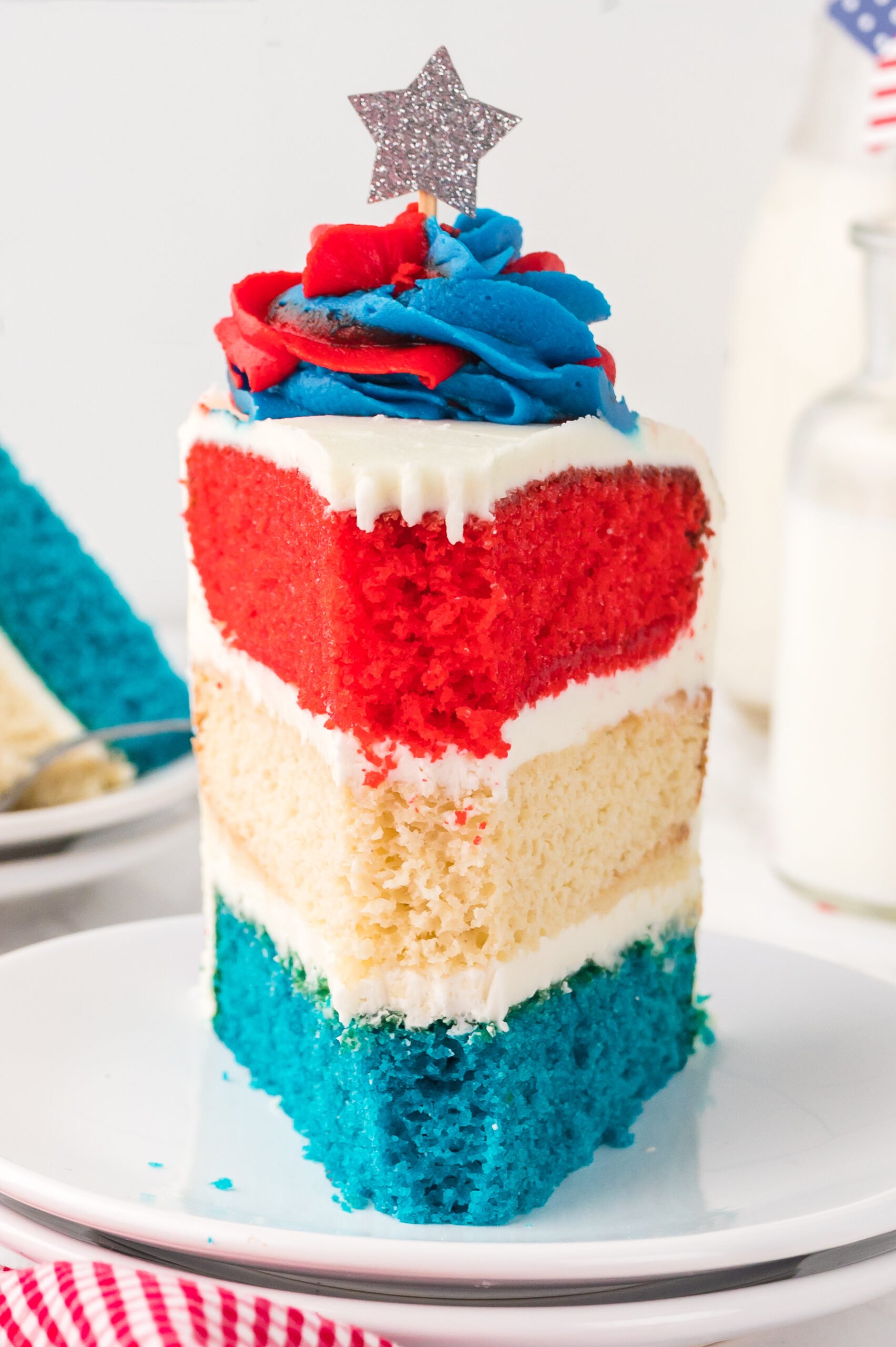 front view of a Slice of American Flag Layered Cake on a white plate with a bite missing