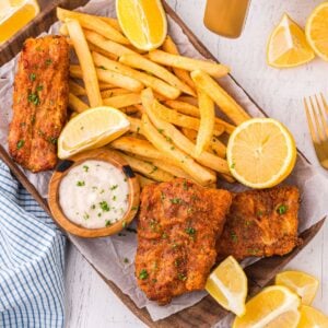 Air Fryer Fish And Chips on a platter with fries and lemon wedges and tartar sauce on side