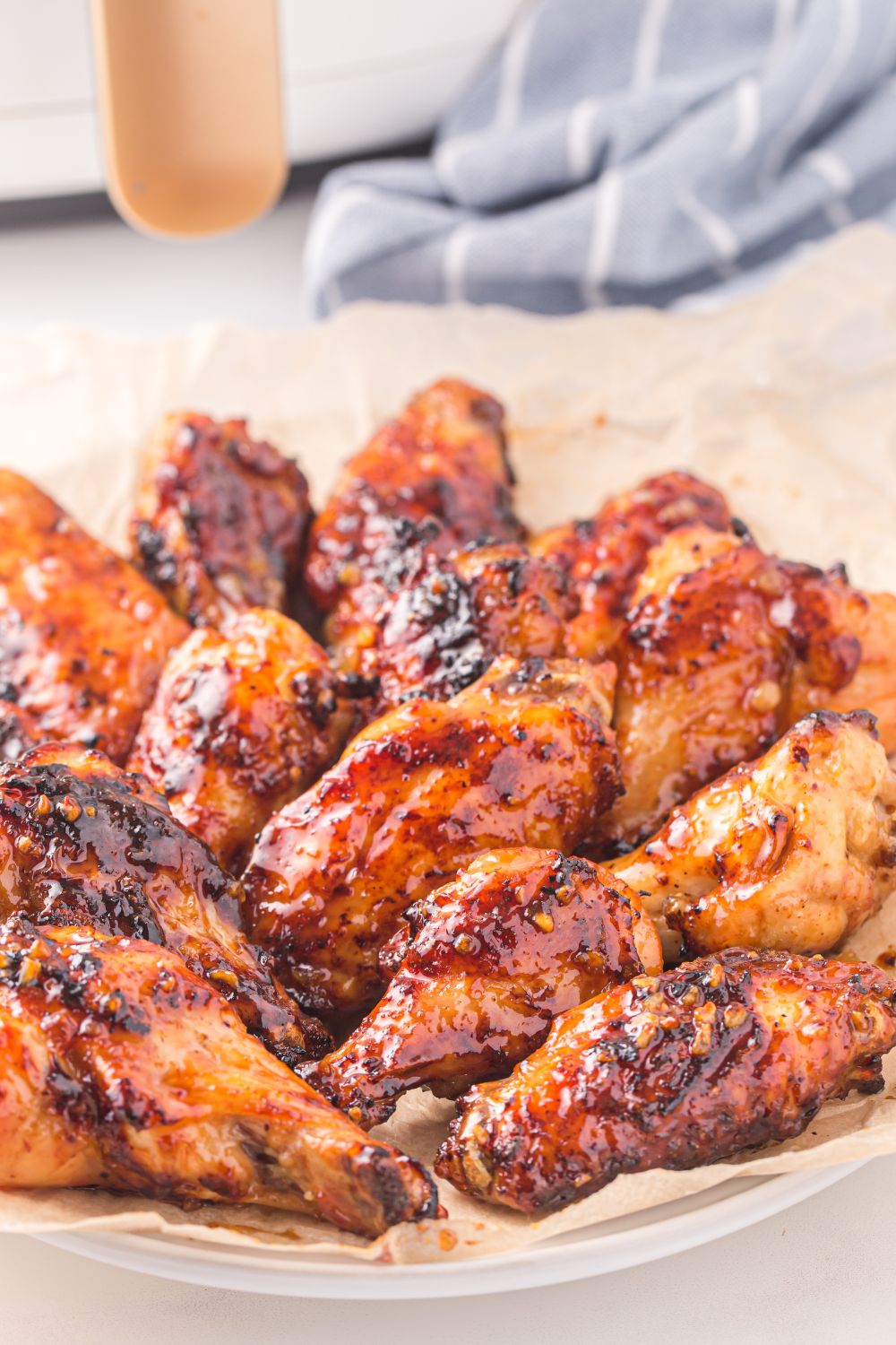Air Fryer Honey Chicken Wings on a plate with a blue striped towel in background 