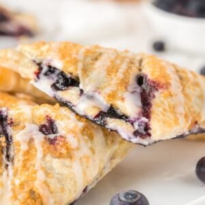 Blueberry Turnovers on plate with fresh blueberries around them on the plate