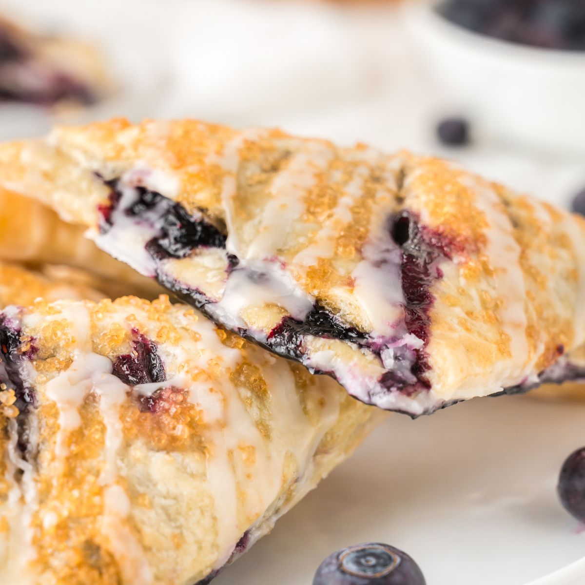 Blueberry Turnovers on plate with fresh blueberries around them on the plate 