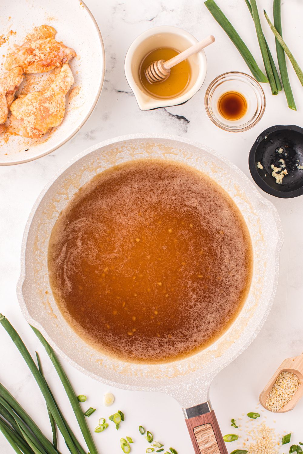 honey sauce in a skillet on table with bowls of ingredients 