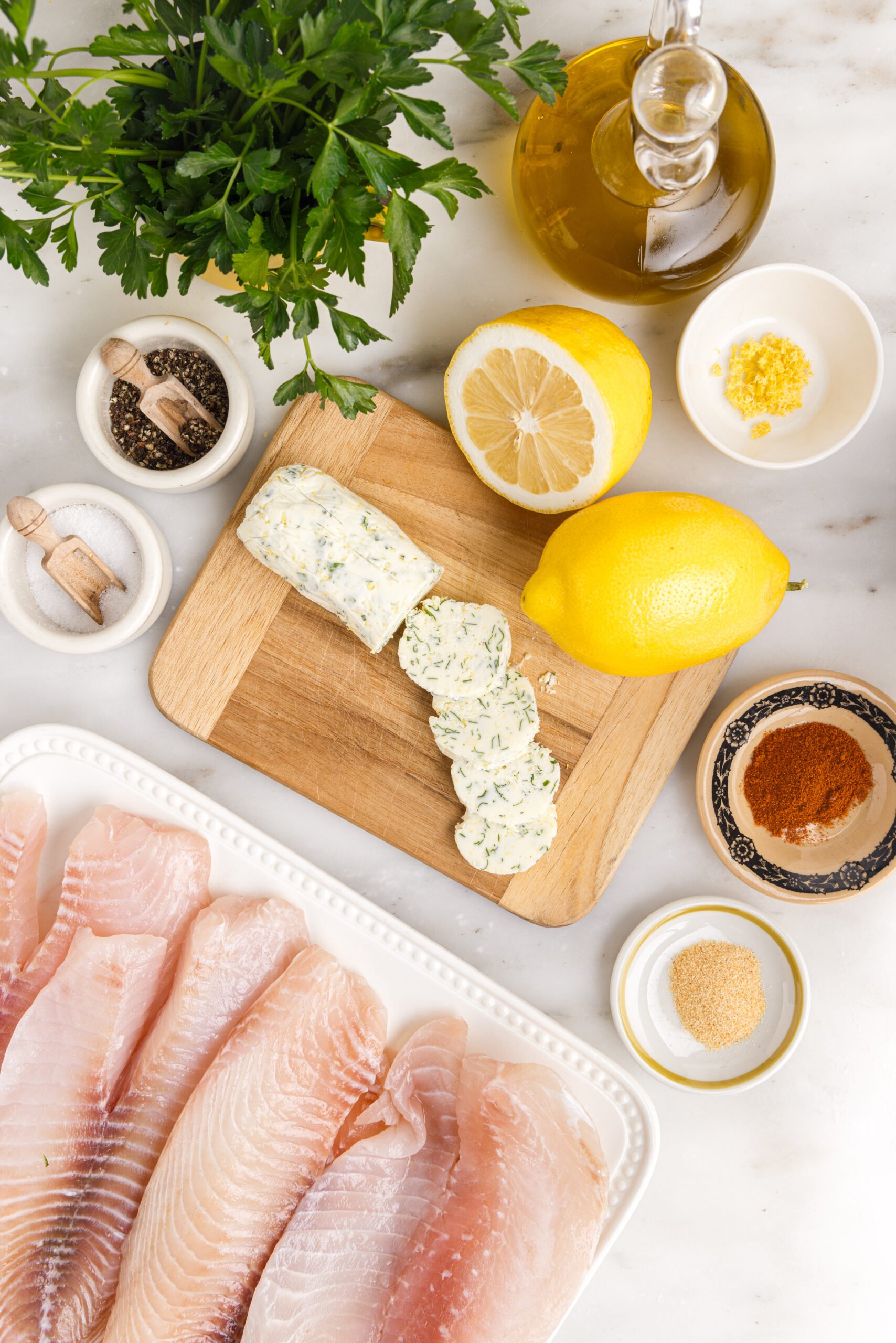 Pan fried tilapia ingredients on a white marble table laid out 