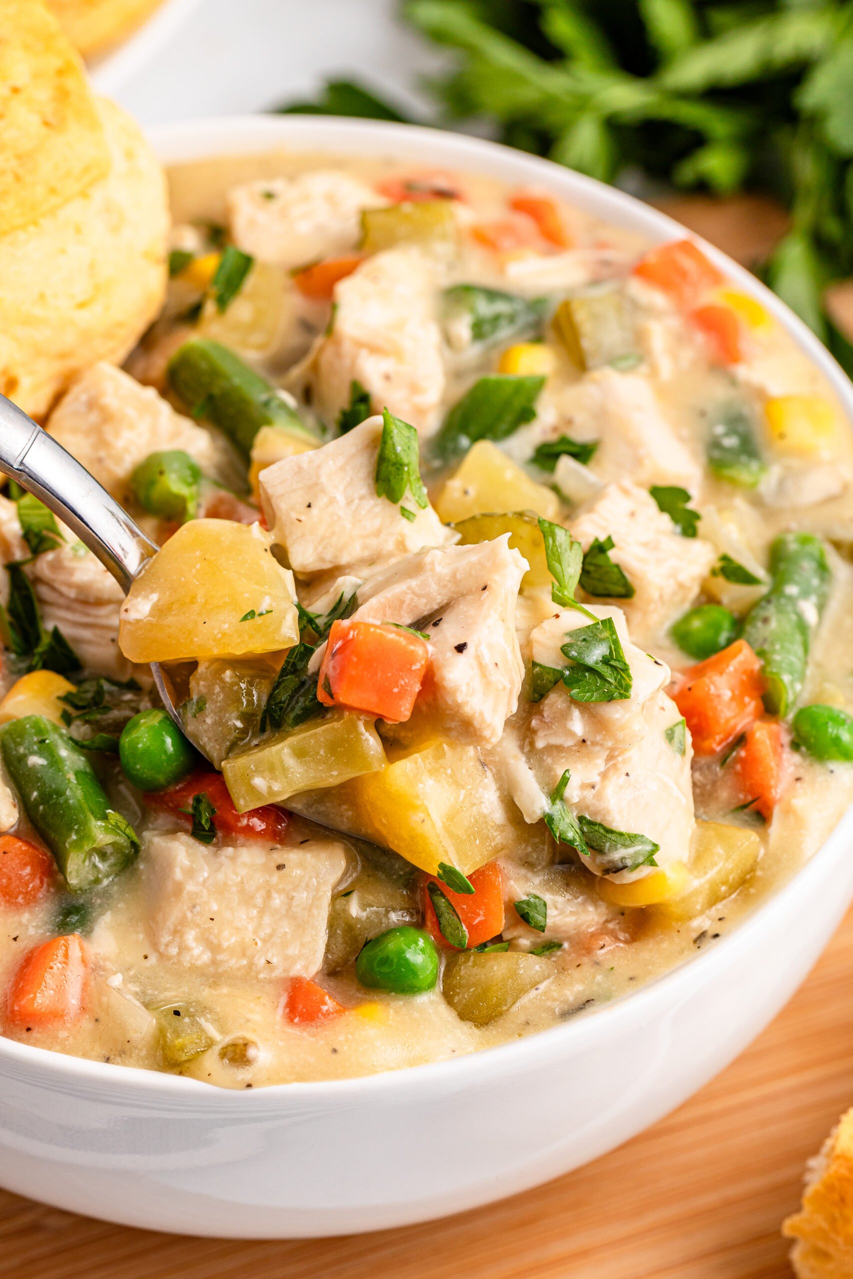 up close shot of the Slow Cooker Chicken Pot Pie in a white bowl with a spoon lifting up some