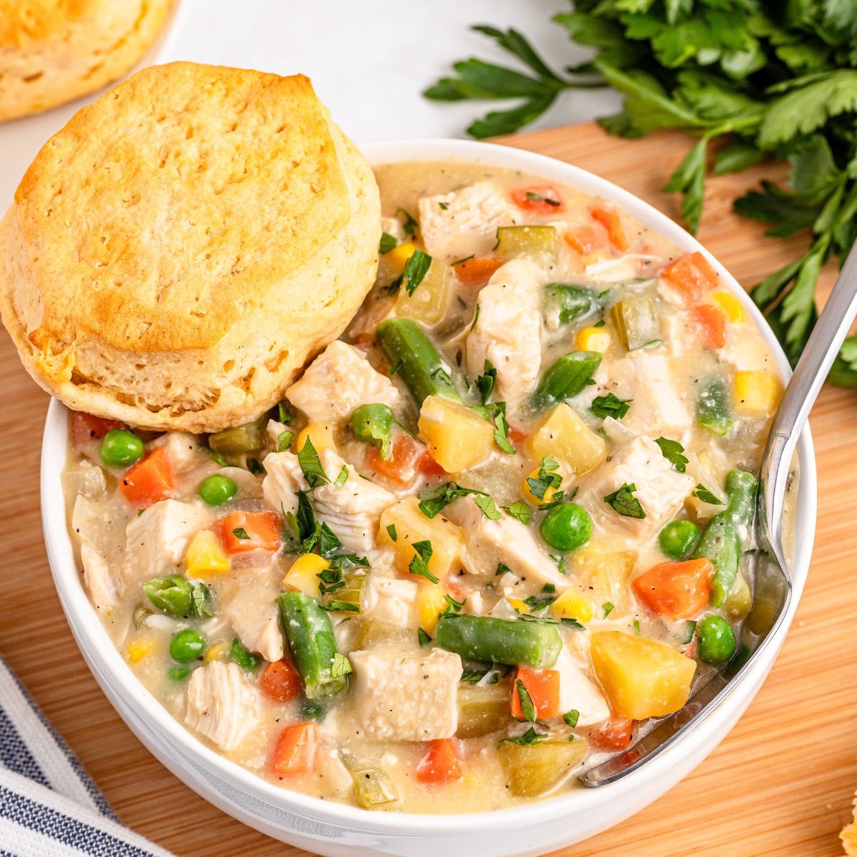 Slow Cooker Chicken Pot Pie in a bowl with a biscuit on side of bowl 