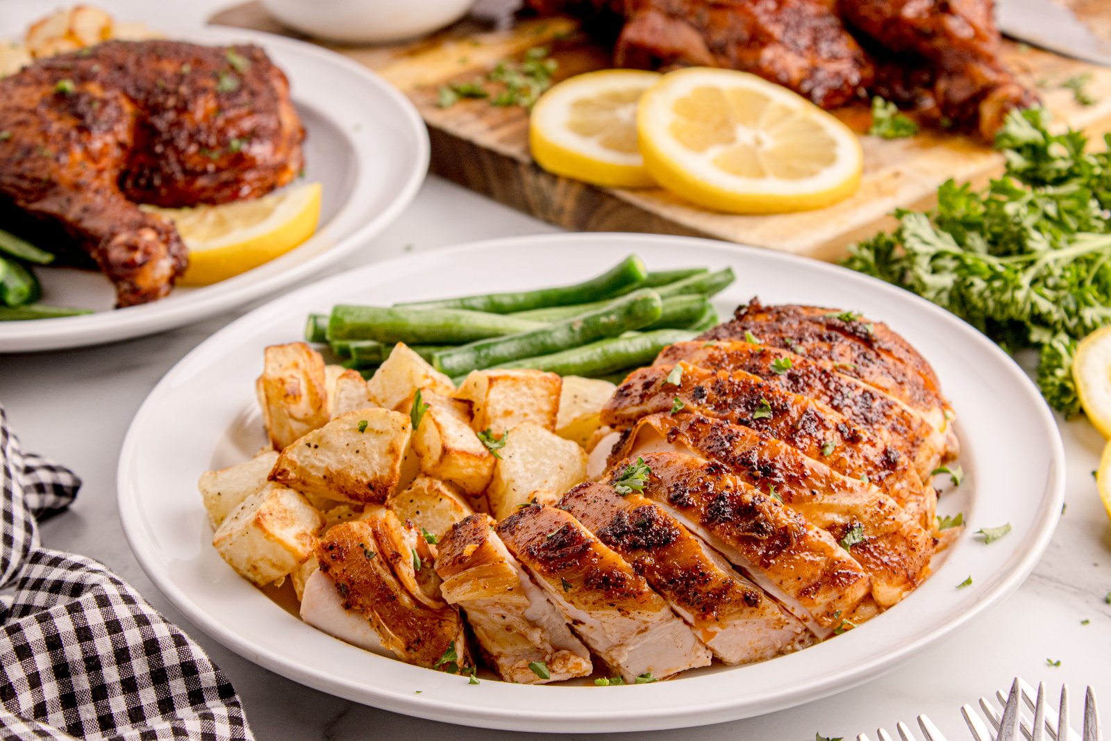 Smoked Whole Chicken on plate with some pieces sliced on it with roasted potatoes and greens