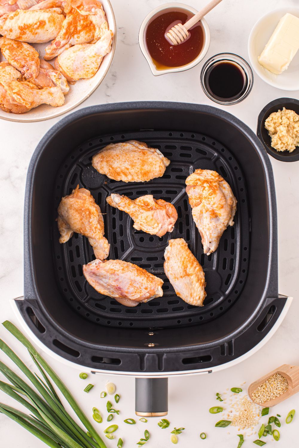 air fryer with chicken wings in an air fryer and sauce ingredients