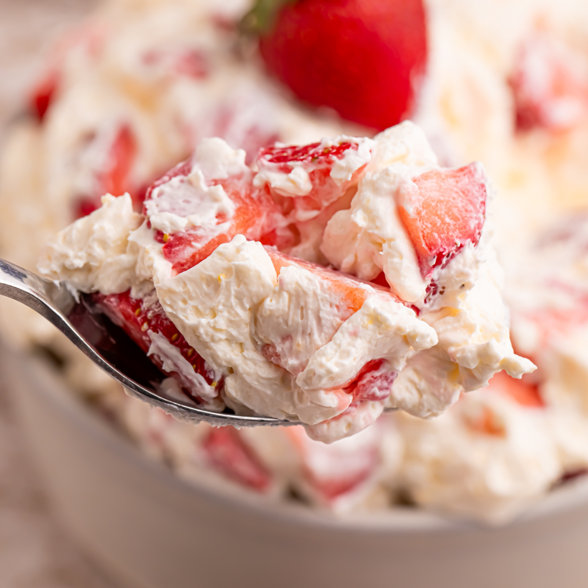 Close up view of the strawberry salad on a silver spoon. 