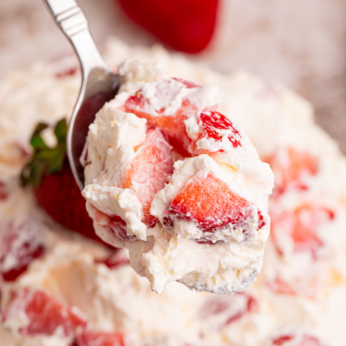 Close up view of the strawberry salad on a silver spoon. 
