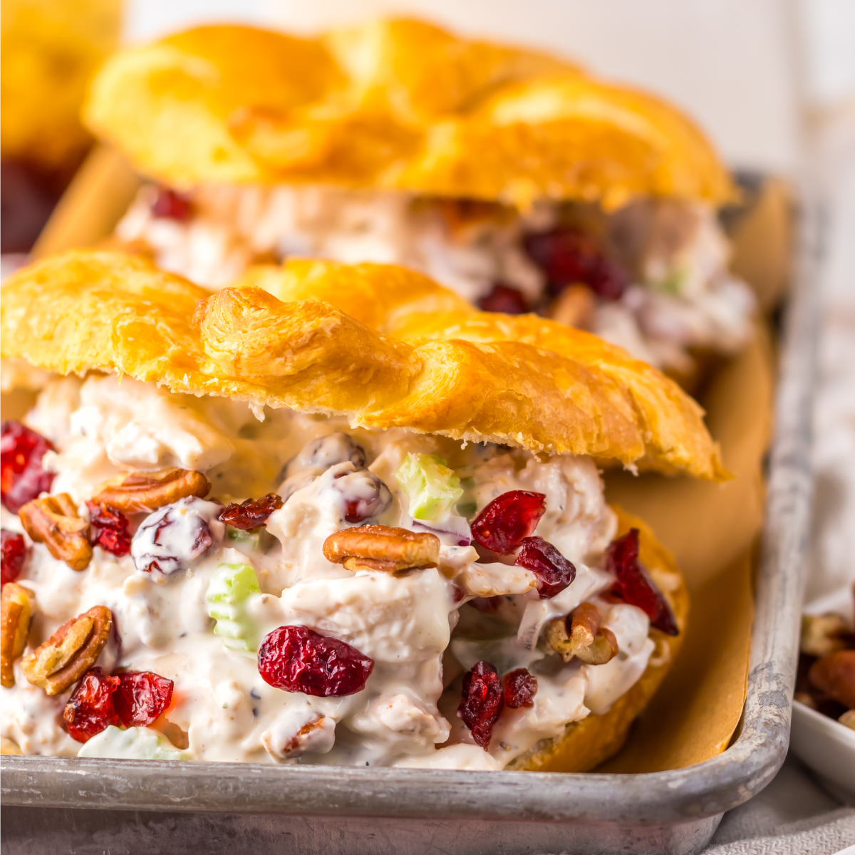 Close up view of a Cranberry Pecan Chicken Salad Croissant on a metal tray.
