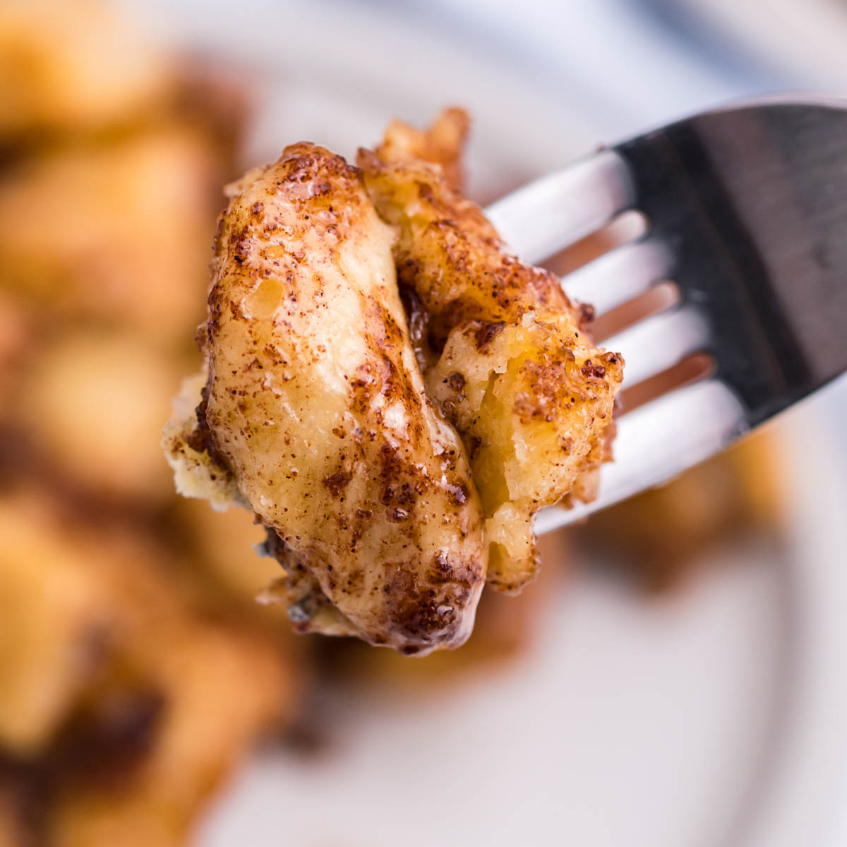 Up close shot of a piece of Cinnamon Roll Casserole on a silver fork. 