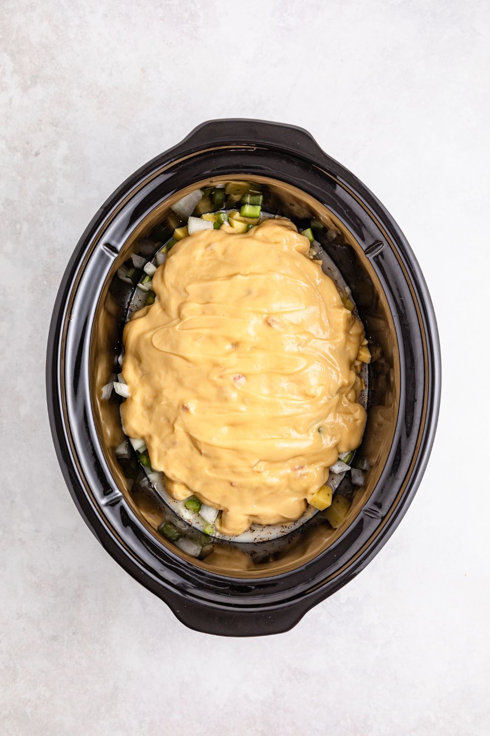 cream of chicken soup poured over veggies in slow cooker on table 