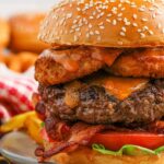 Close up view of a cowboy burger on a plate with a pickle on top