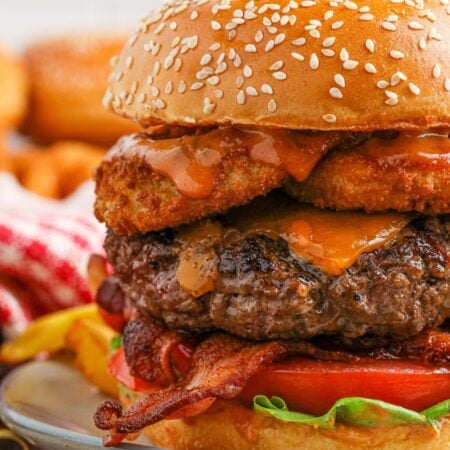 Close up view of a cowboy burger on a plate with a pickle on top