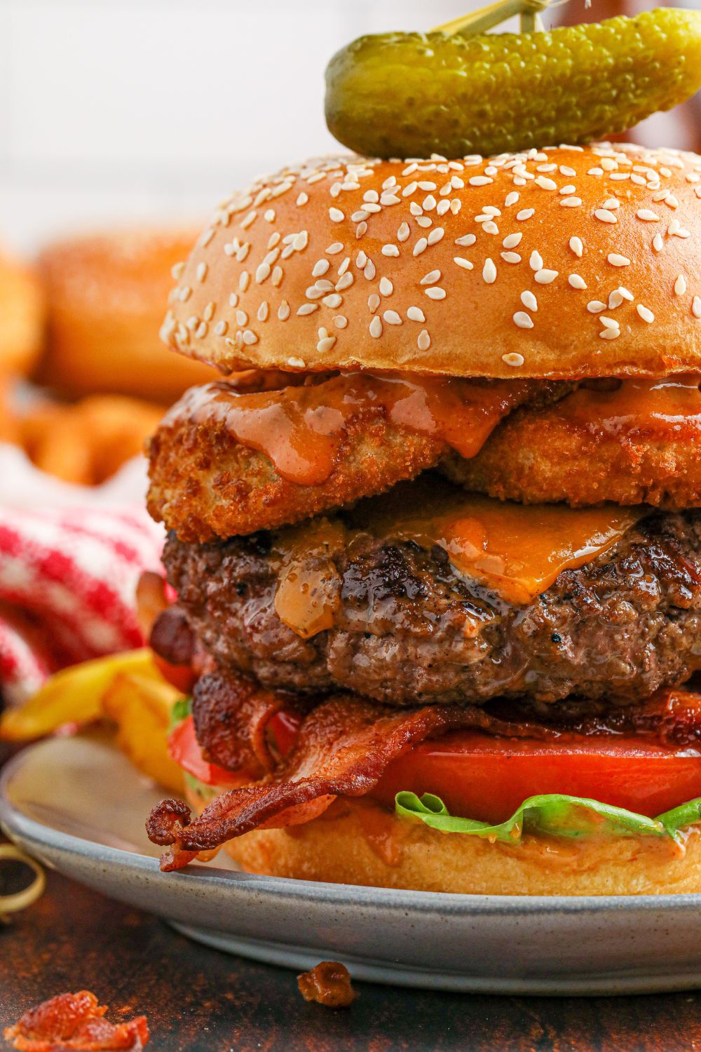 Close up view of a cowboy burger on a plate with a pickle on top 