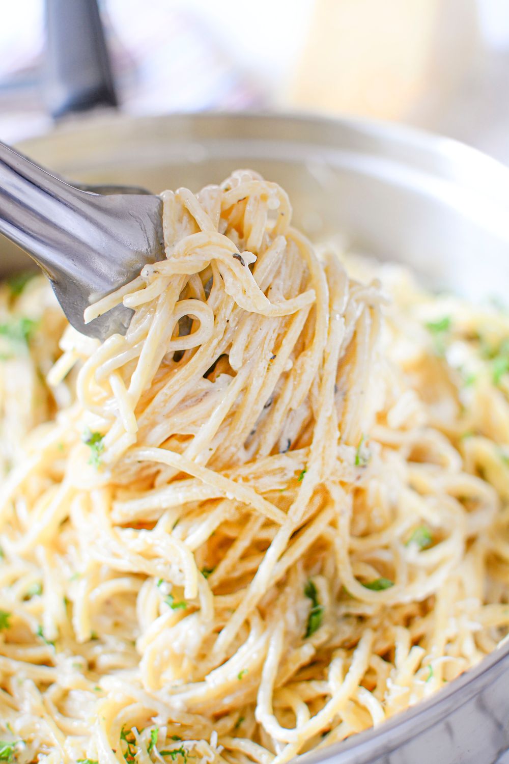 Garlic Parmesan Pasta being lifted out of pan with tongs to show how creamy it is 