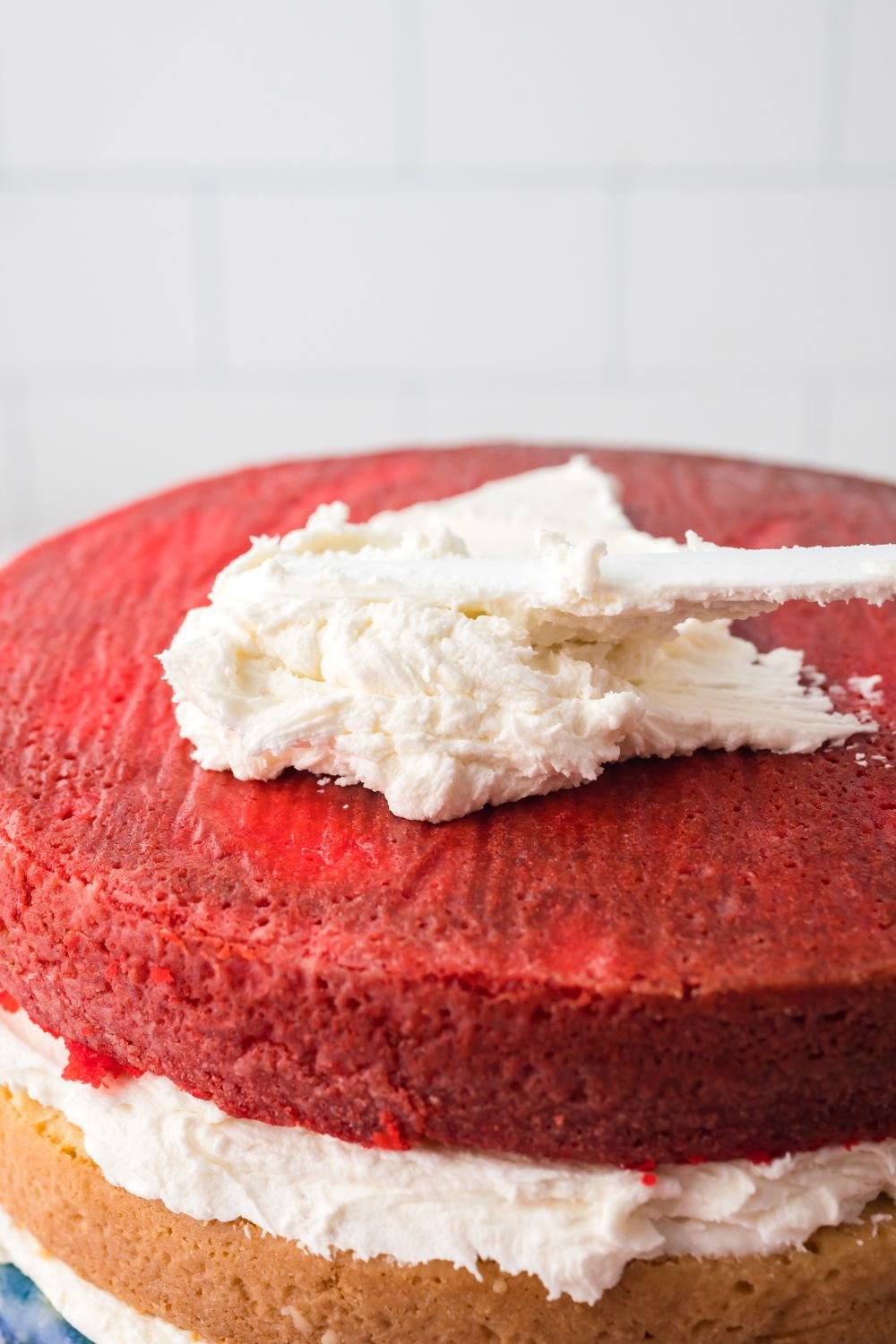 white frosting spreading onto a red layer of this American Flag Cake 