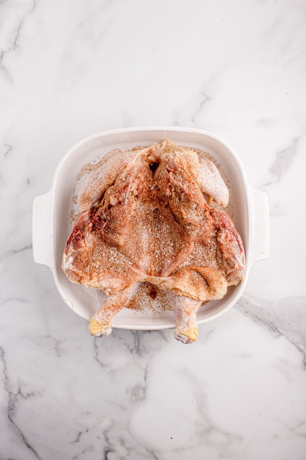 broken down raw chicken seasoned with dry rub 