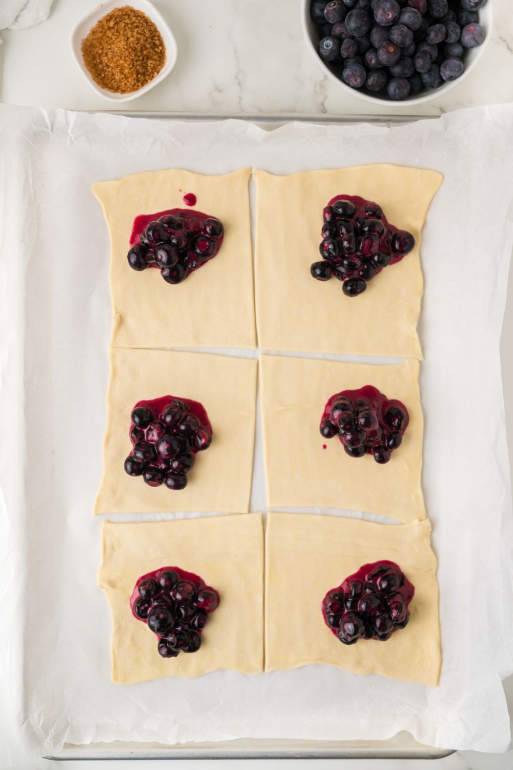 pastry cut in squares and topped with a blueberry filling for Blueberry Turnovers