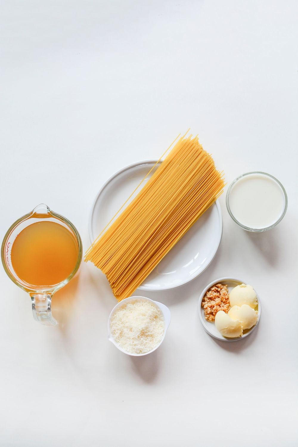 ingredients for Garlic Parmesan Pasta recipe in single serve bowls on white table 