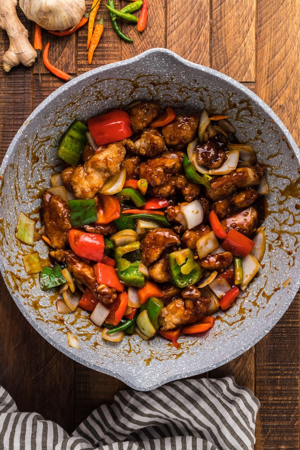 General Tso Chicken being tossed in sauce with veggies in bowl 